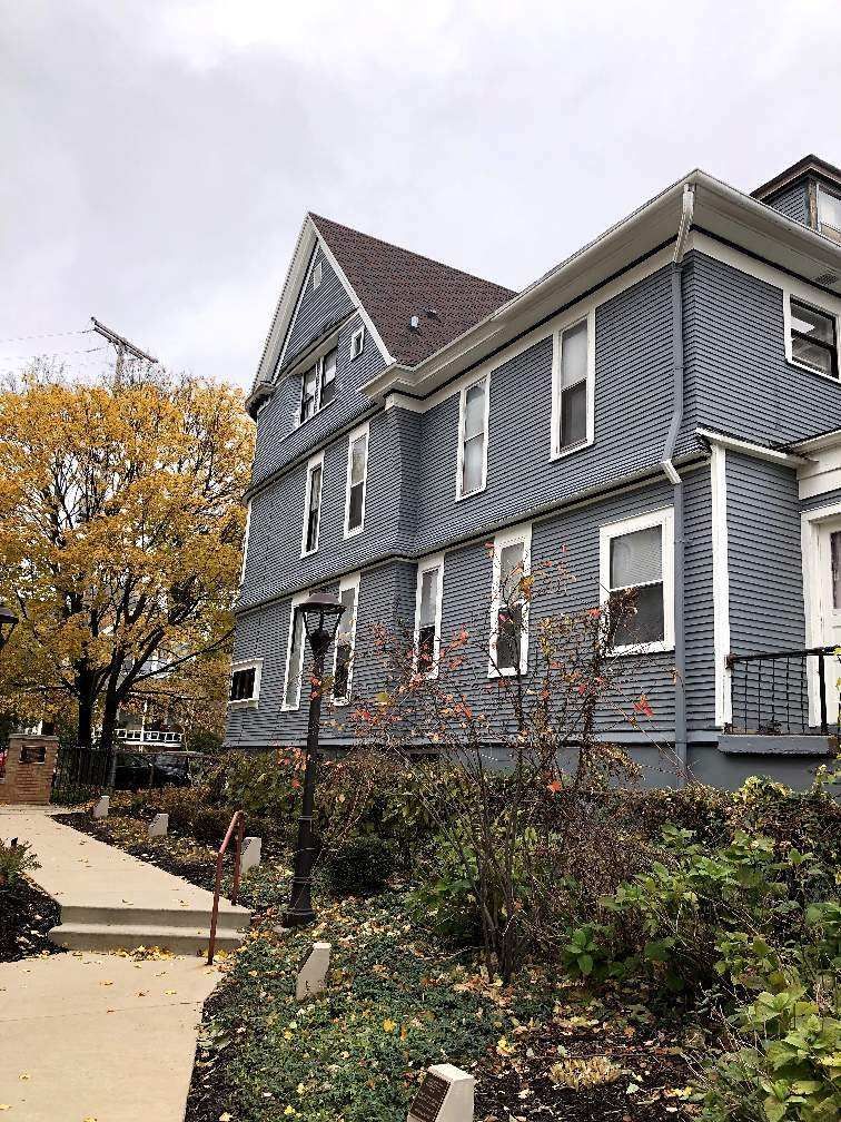 A large blue house with a lot of windows is surrounded by trees and bushes.