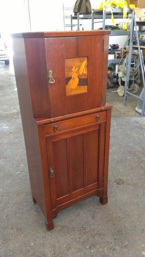 A wooden cabinet with a deer on it is sitting on a concrete floor.