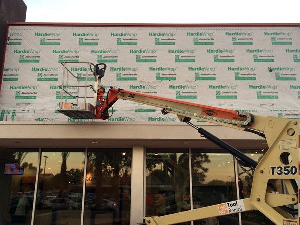 A crane is being used to install a sign on the side of a building.
