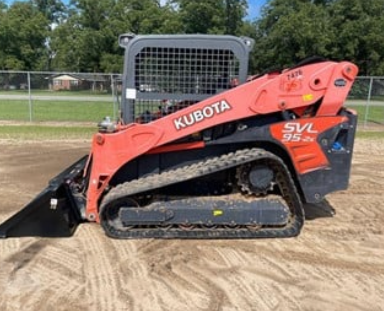 A kubota skid steer is parked in a dirt field