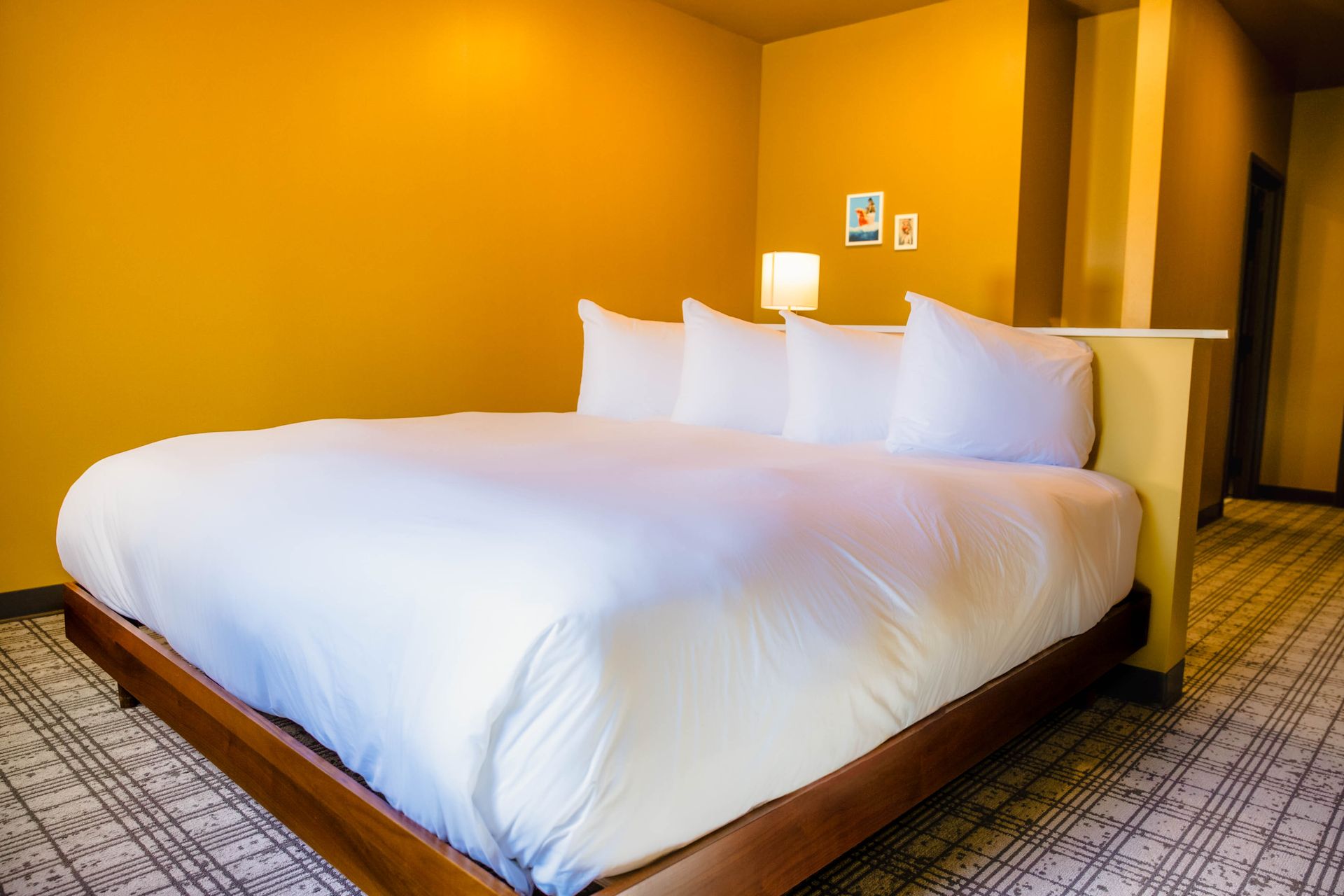 A neatly made bed with white linens and pillows, flanked by lamps on tables, against teal walls in a hotel room.