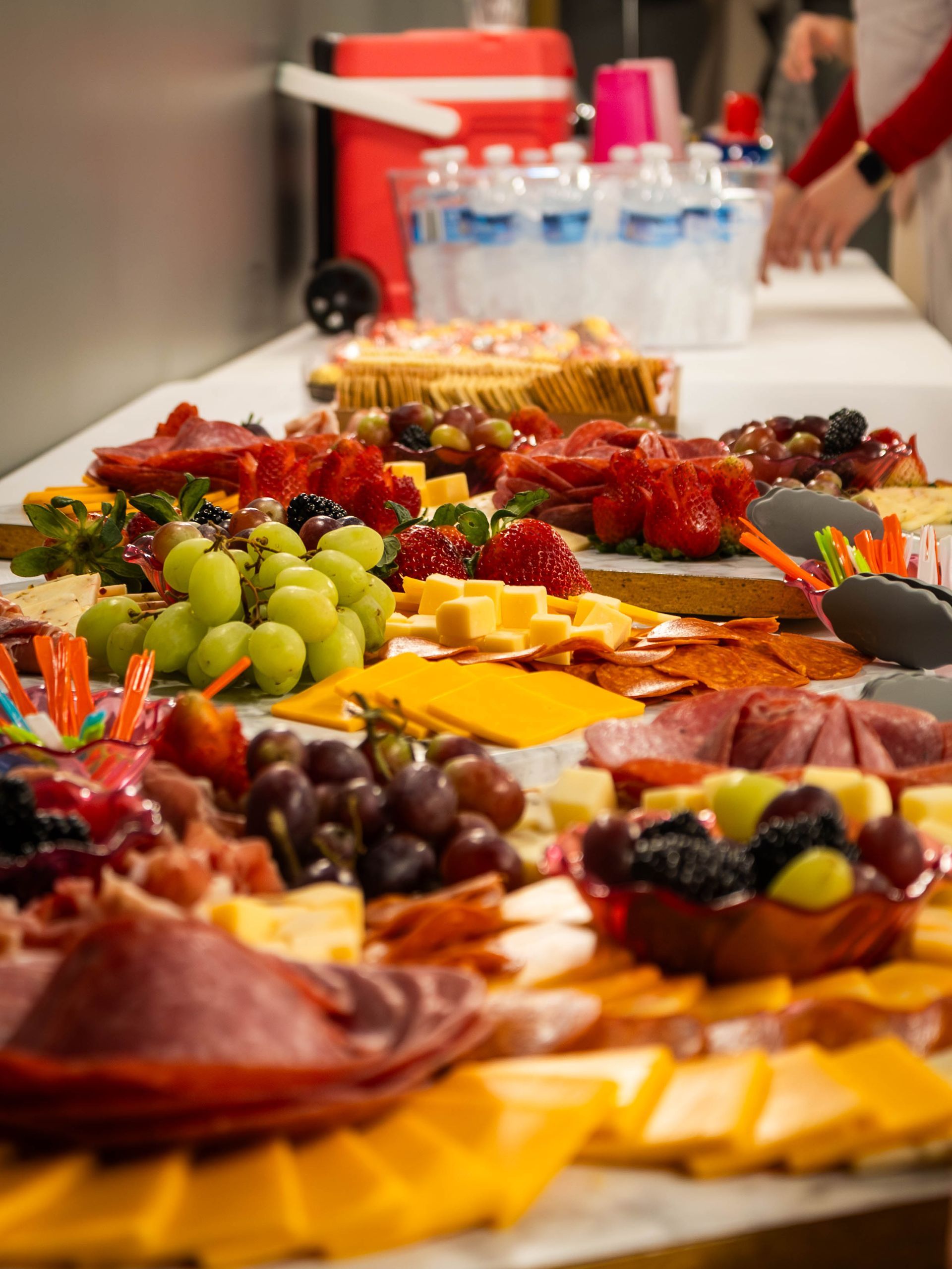 A bountiful charcuterie spread featuring various cheeses, meats, grapes, and berries arranged on a long table.