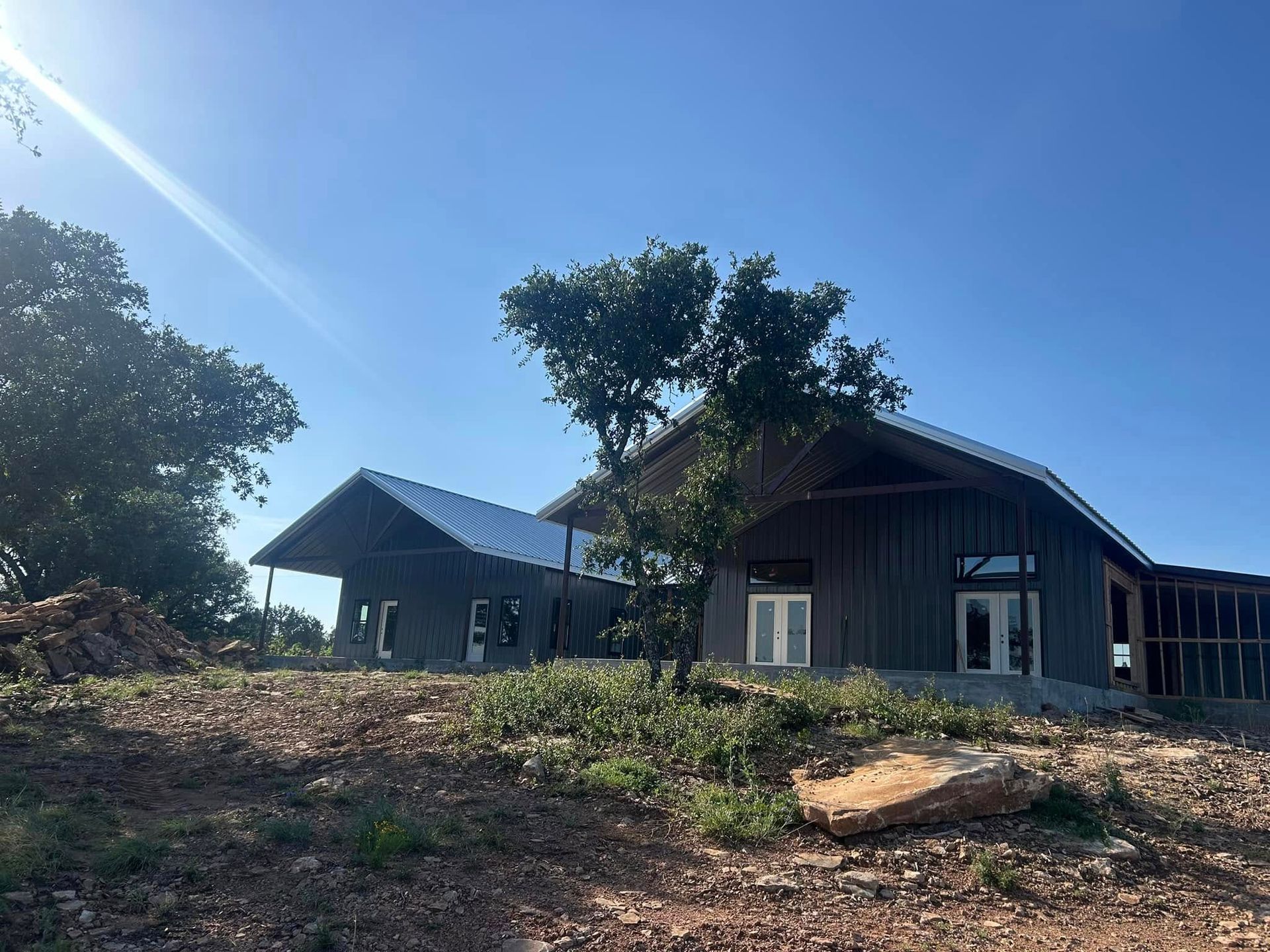 A large house is being built on top of a dirt hill.