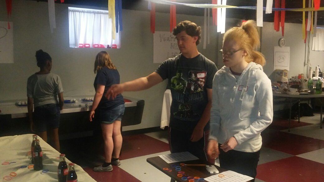 A boy and a girl are standing next to each other in a room.