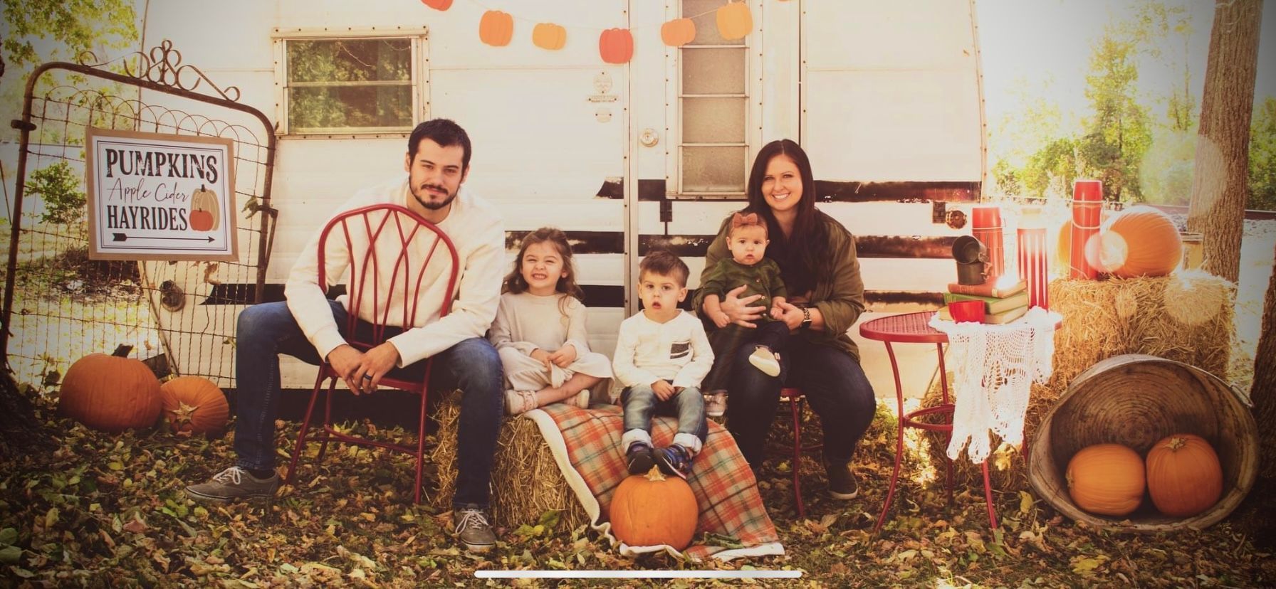 A family is posing for a picture at a pumpkin patch.