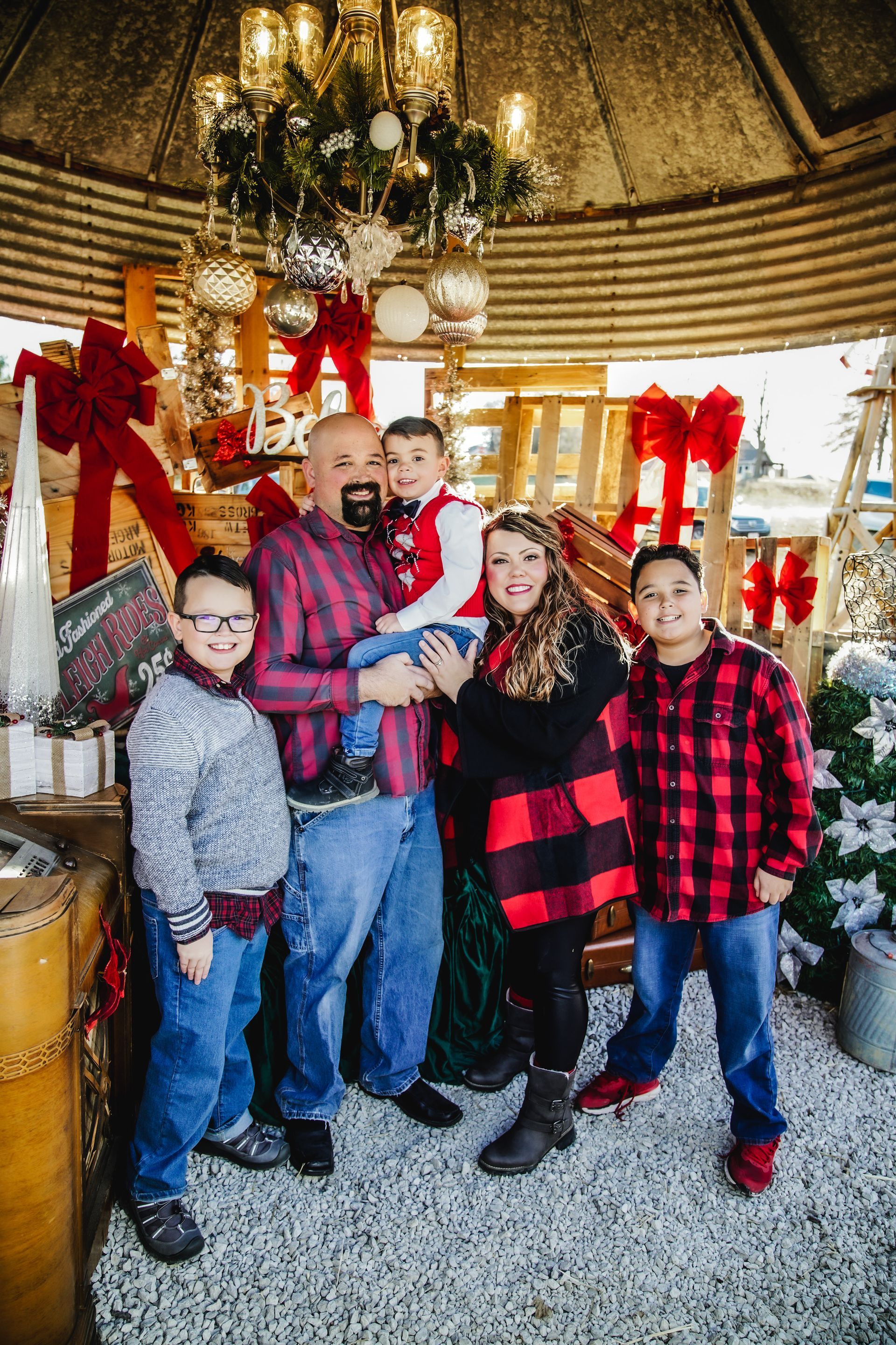 A family is posing for a picture in a gazebo decorated for christmas.