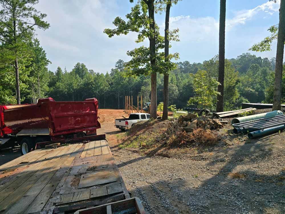 A red dump truck is parked on the side of a dirt road.
