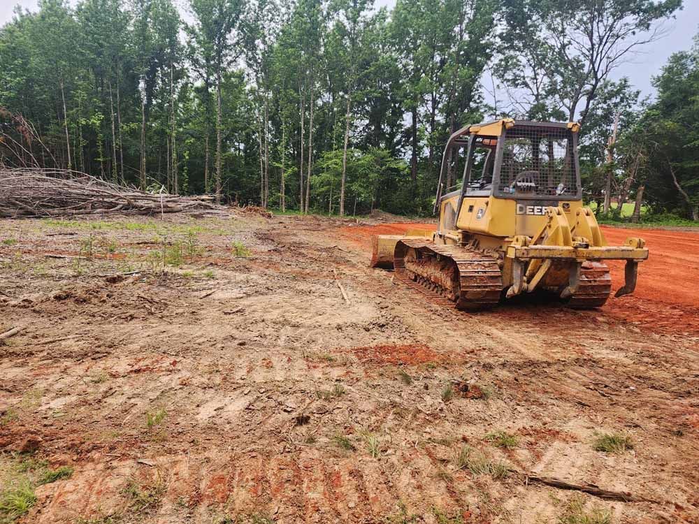 A bulldozer is driving through a dirt field.