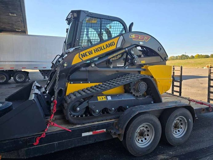 A new holland skid steer is sitting on top of a trailer.