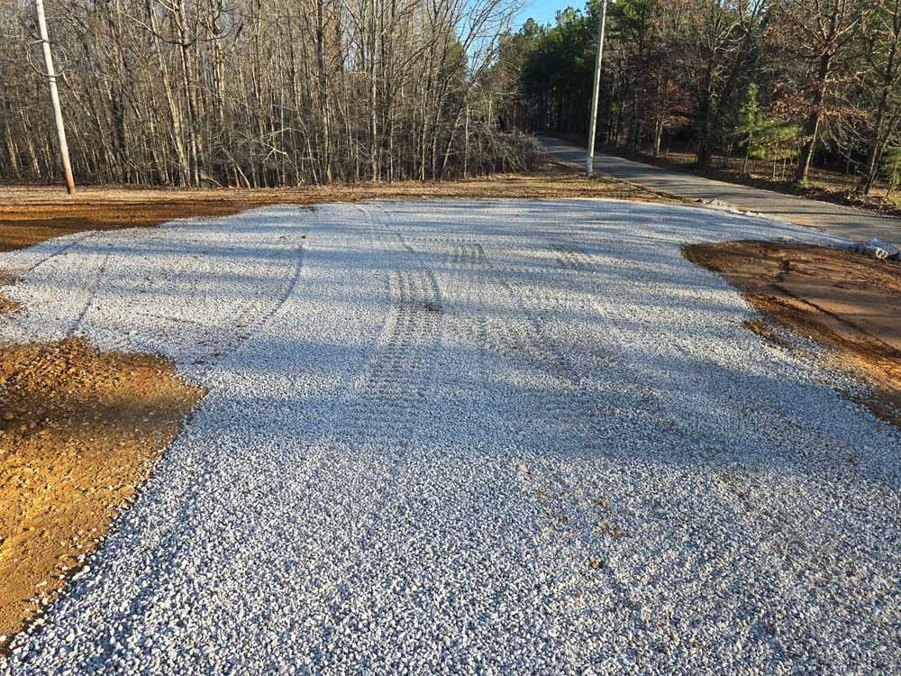 A gravel road with trees in the background is being built.