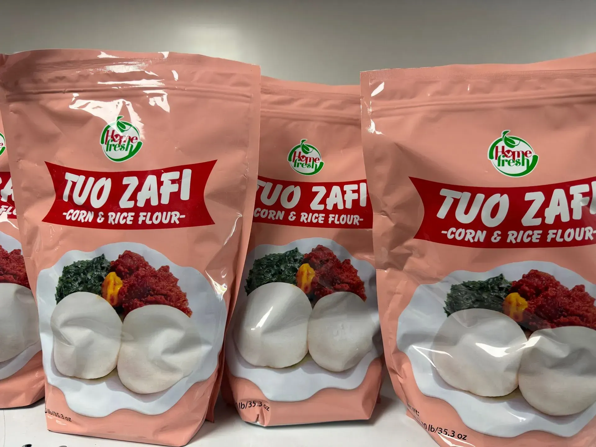 Four bags of tuo zafi corn and rice flour are lined up on a table.