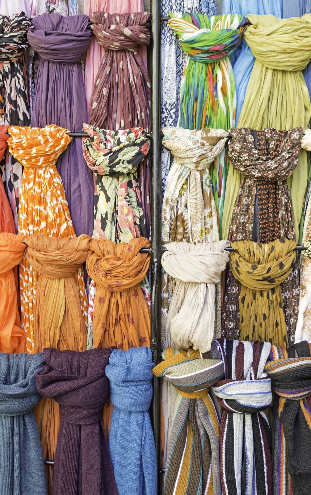 A bunch of scarves are hanging on a rack in a store.