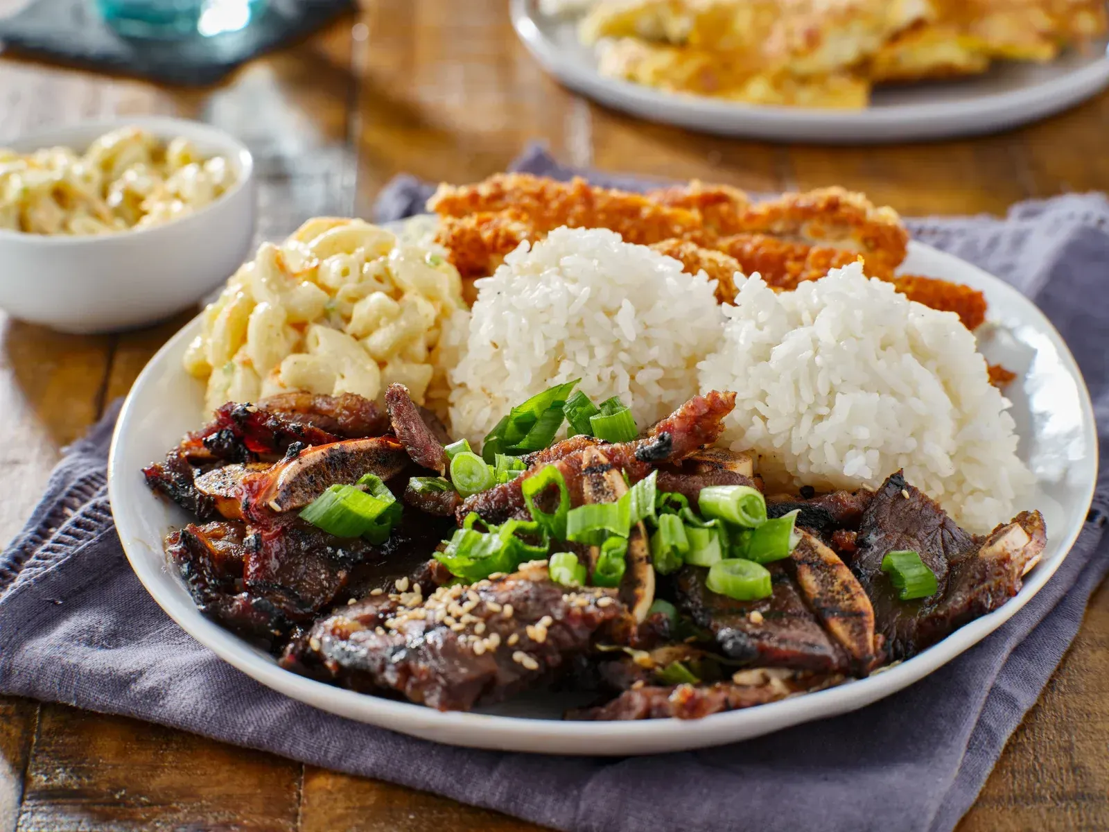 A white plate topped with meat , rice , macaroni and cheese and chicken.