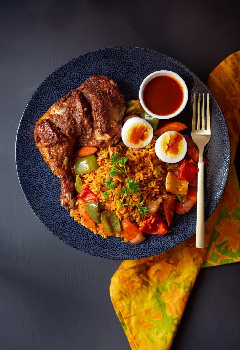 A plate of food with meat , rice , vegetables and a fork on a table.