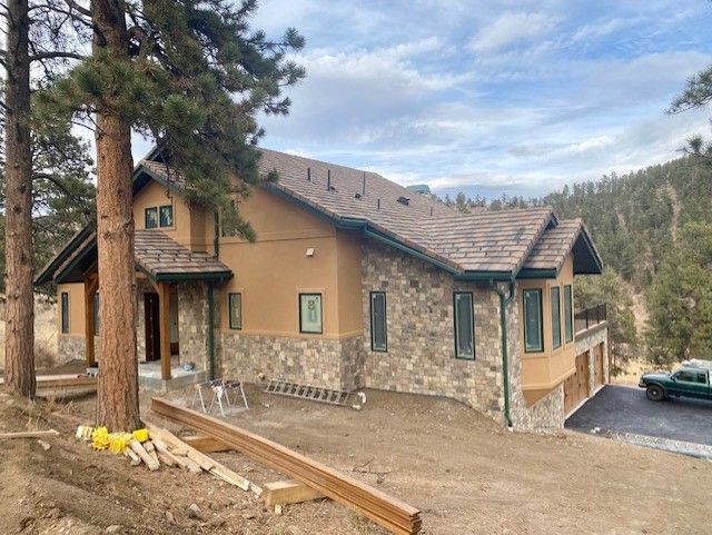 Large house is sitting on top of a hill surrounded by trees – Evergreen, CO - Elevated Roofing