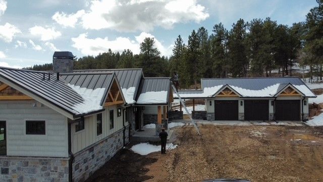 An aerial view of a house under construction with snow on the roof – Evergreen, CO - Elevated Roofing
