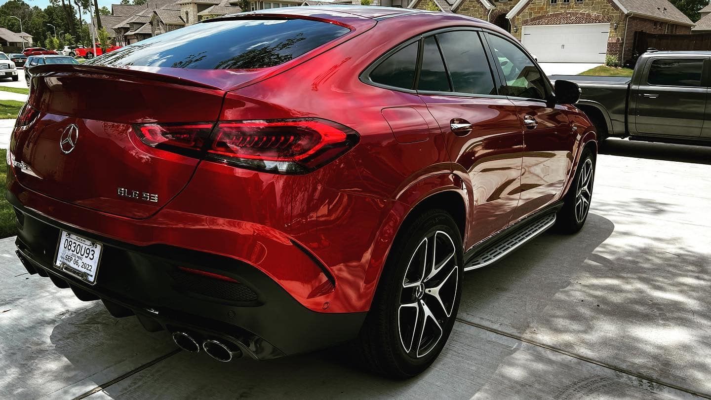 Red Mercedes-Benz GLE Coupe parked on a driveway with houses in the background.