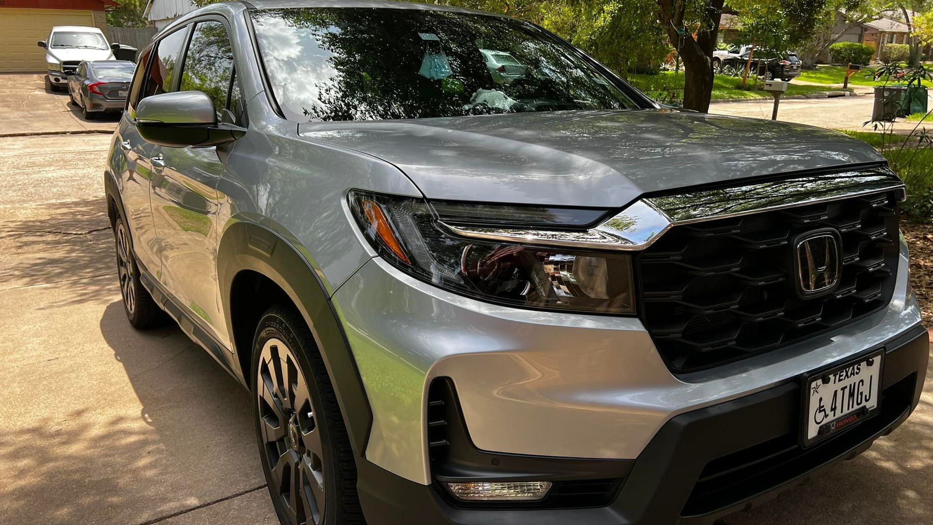 Silver Honda Passport SUV parked in a driveway on a sunny day.