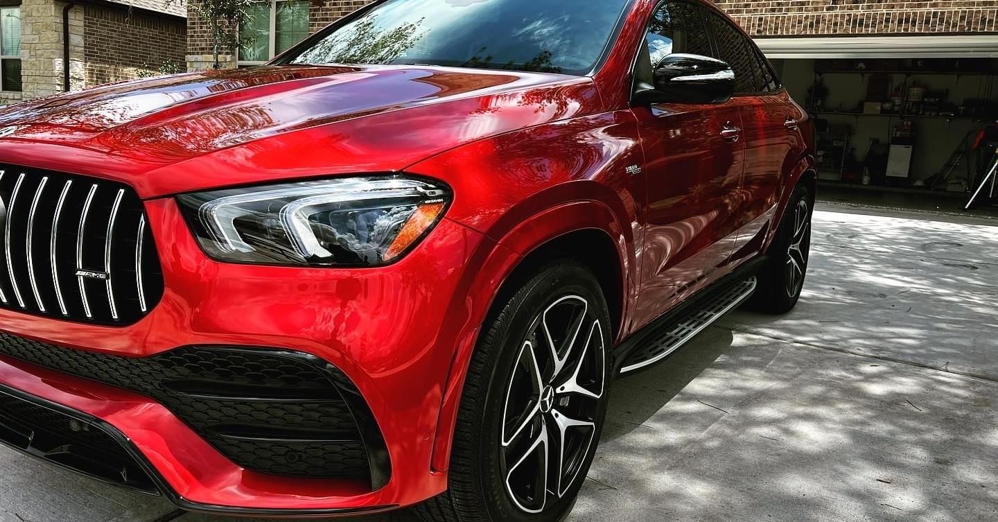 Red Mercedes-AMG GLE SUV parked in a driveway, with black grill and wheels.
