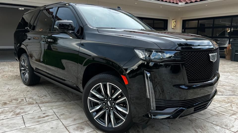 Black Cadillac Escalade SUV parked in front of a house.