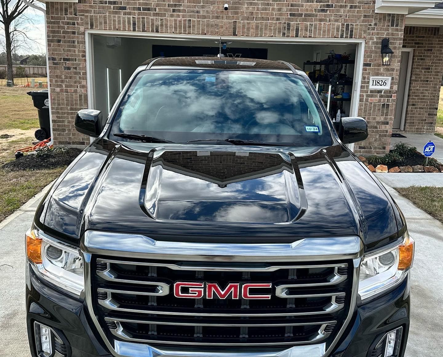 Black GMC truck parked in front of a brick house with an open garage.
