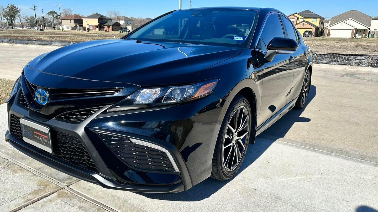 Black Toyota Camry Hybrid sedan parked on a sunny day.