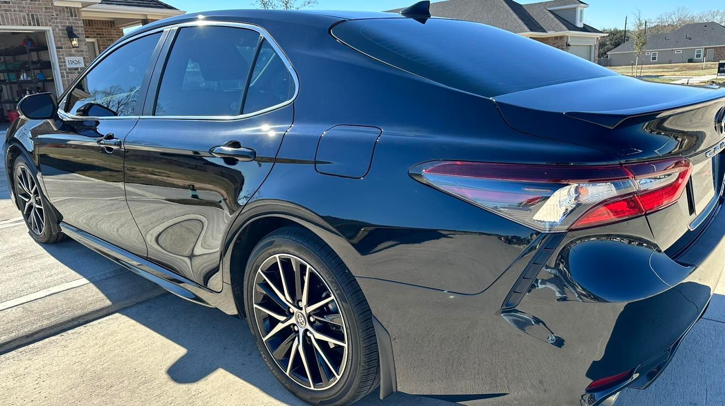 Black Toyota Camry sedan parked outside on a sunny day.