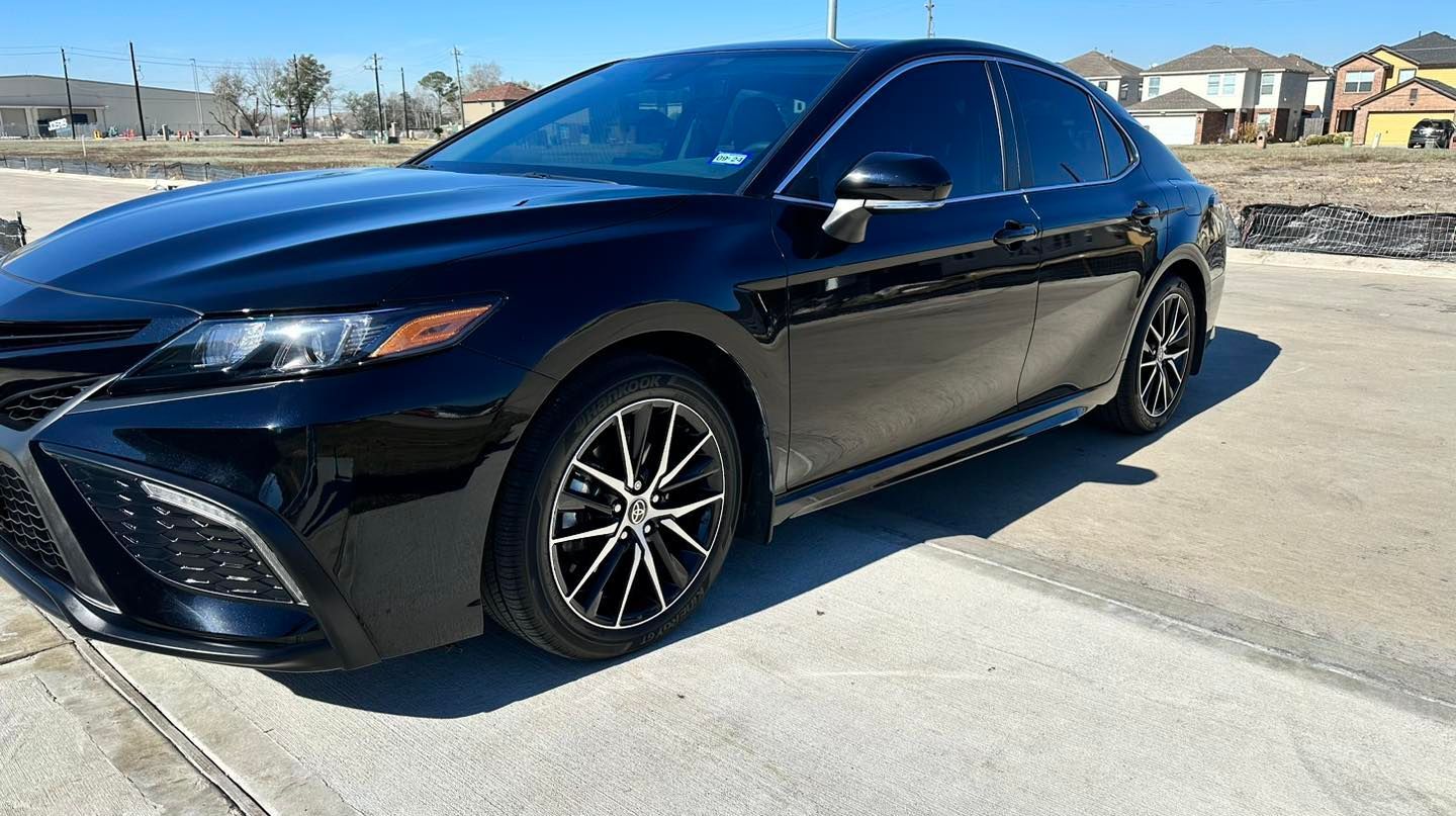 Black Toyota Camry parked outdoors on a sunny day.
