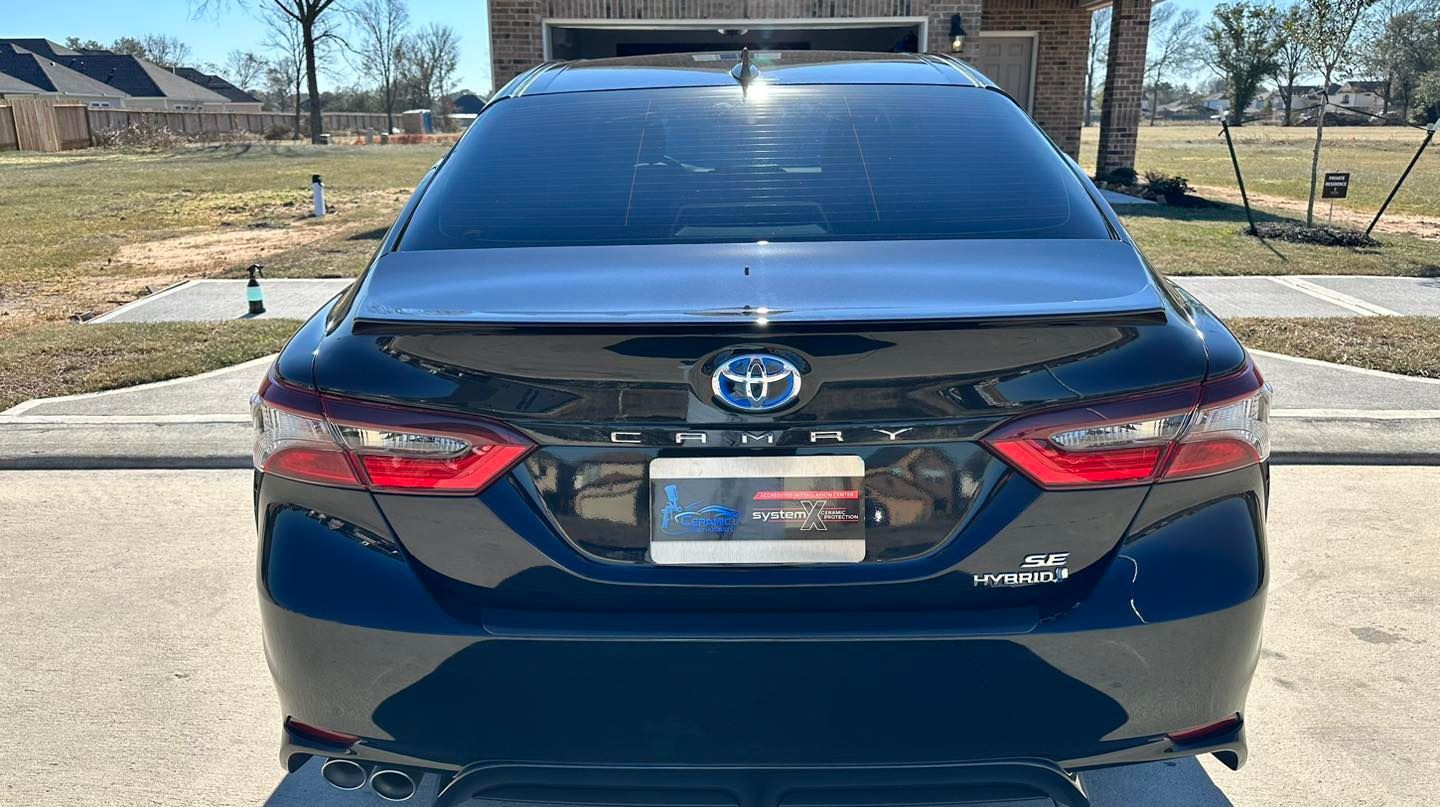 Black Toyota Camry from the rear, tinted windows, license plate, parked outdoors.