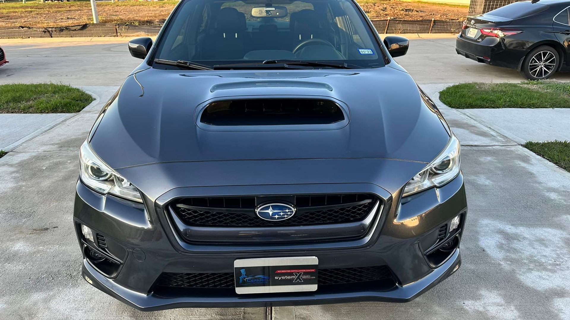 Gray Subaru WRX, front view, outdoors, parked on a driveway.