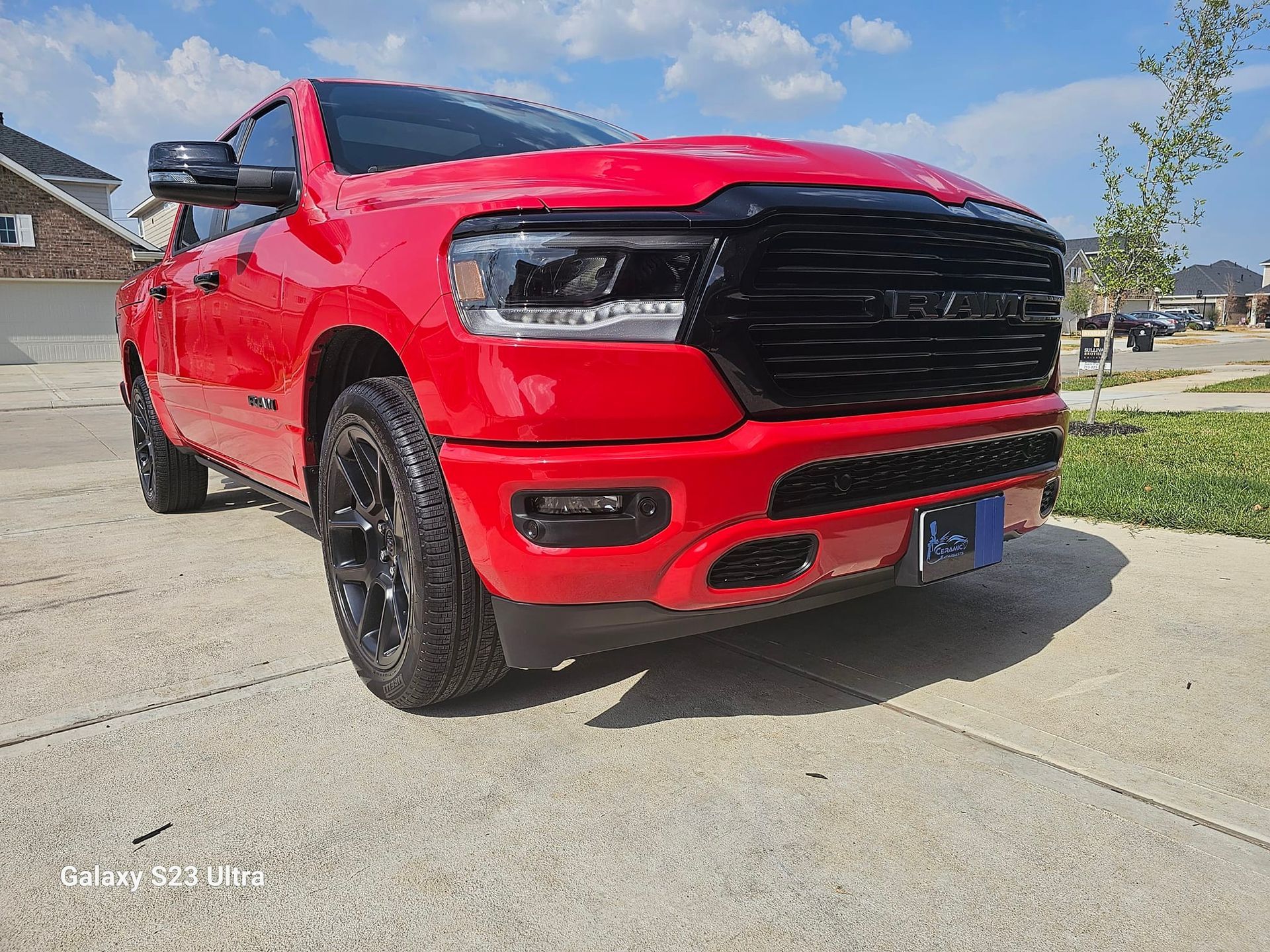 Red Ram pickup truck parked on a driveway in front of a house on a sunny day.