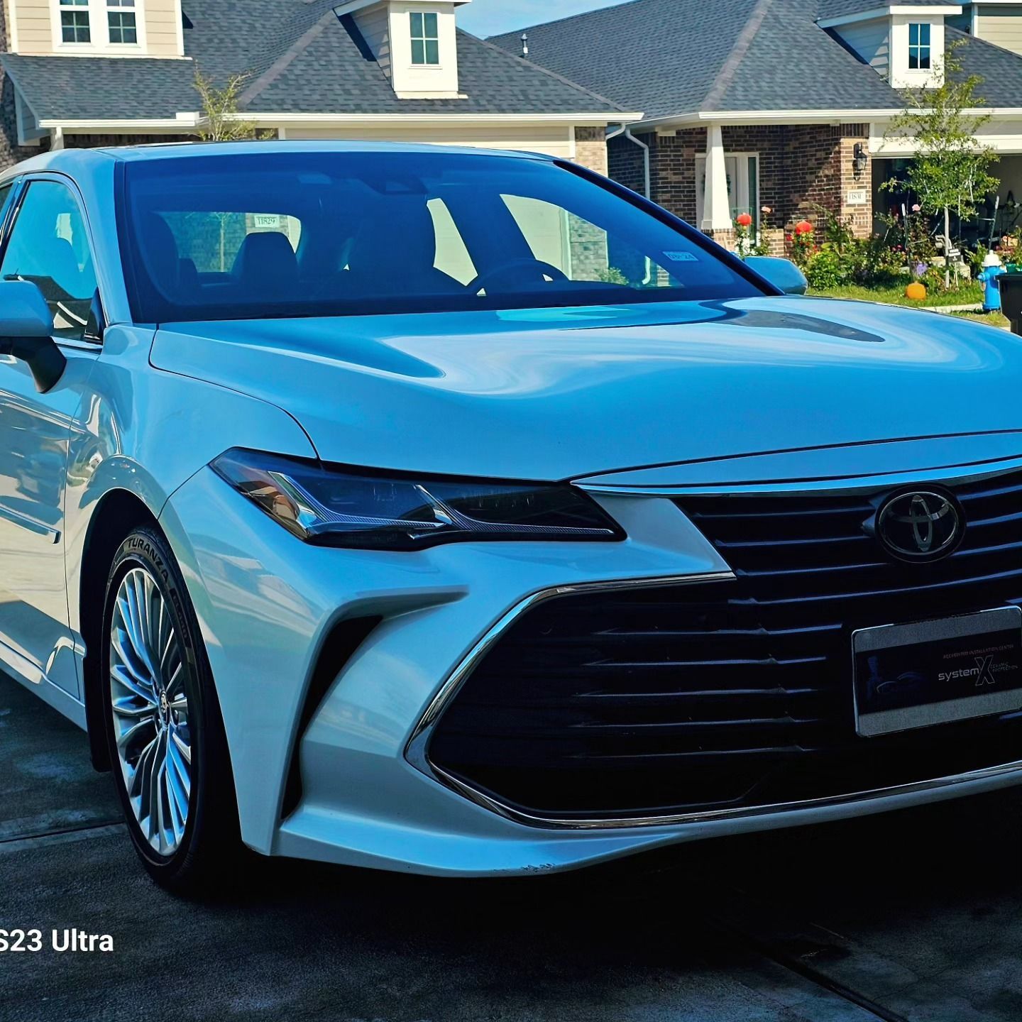 White Toyota Avalon parked in front of a house.