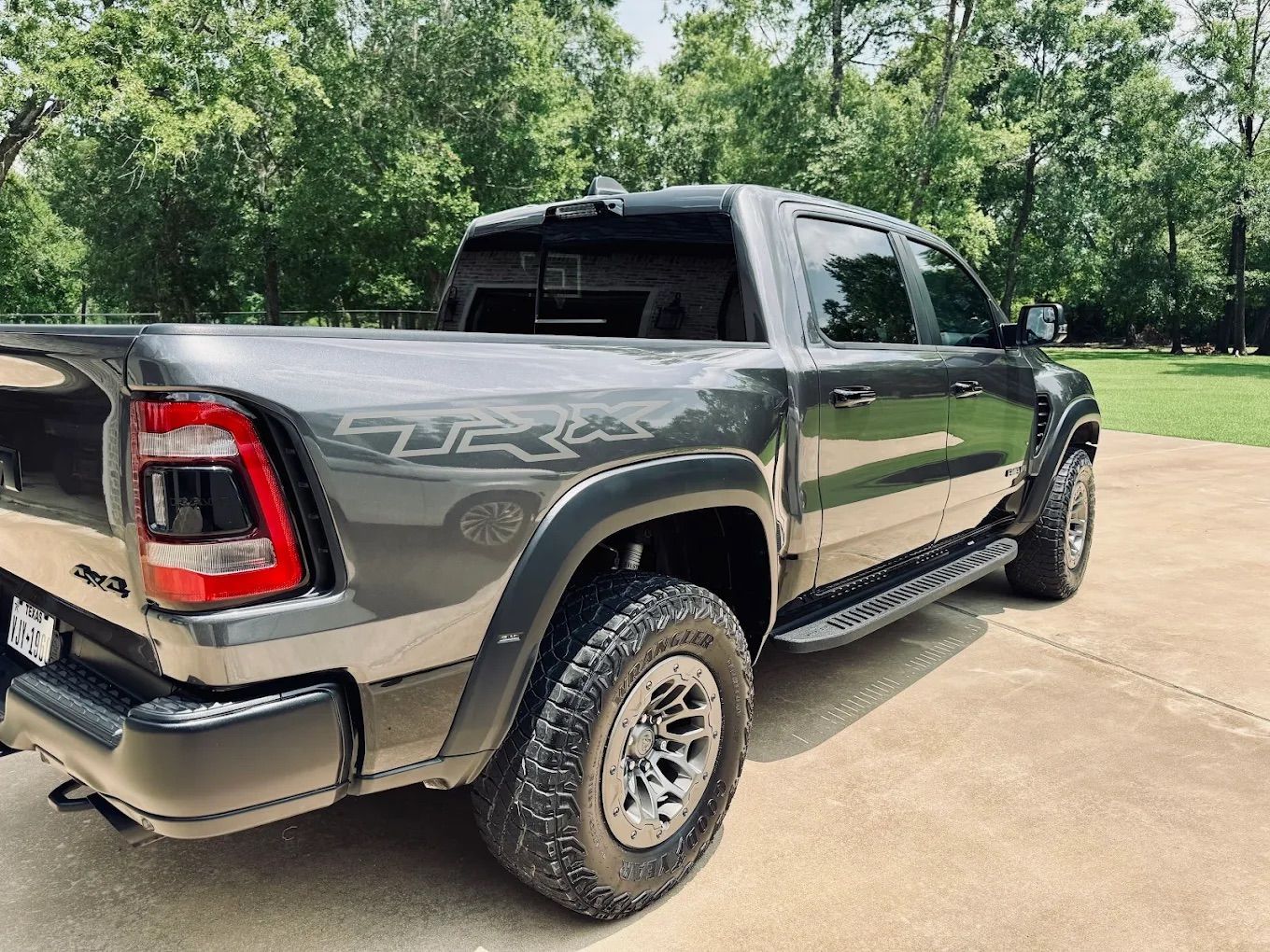 Gray Ram TRX pickup truck parked on a concrete driveway, with a wooded background.