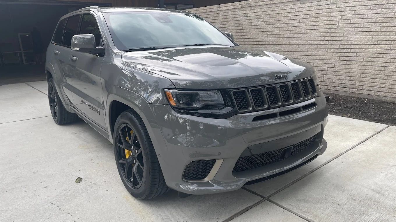 A person holding a baby up in the air indoors near a window, baby smiling.