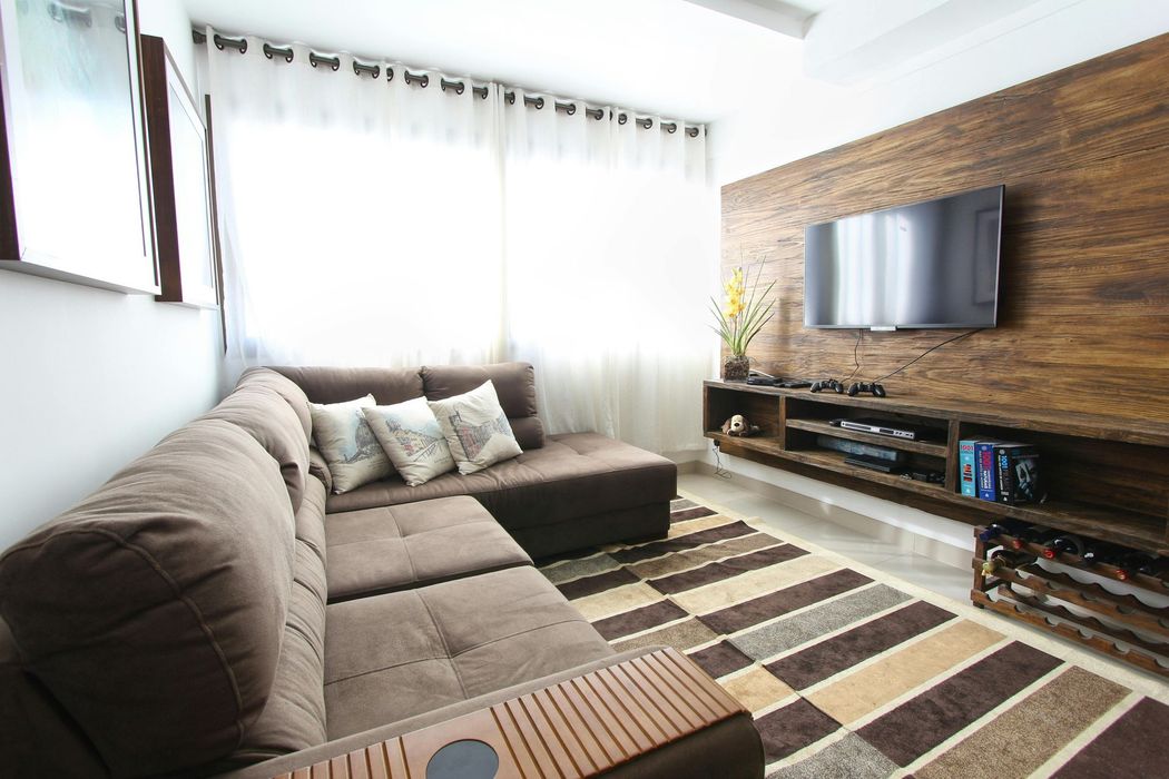 Cozy living room with brown sectional sofa, TV on wood panel wall, and patterned rug.