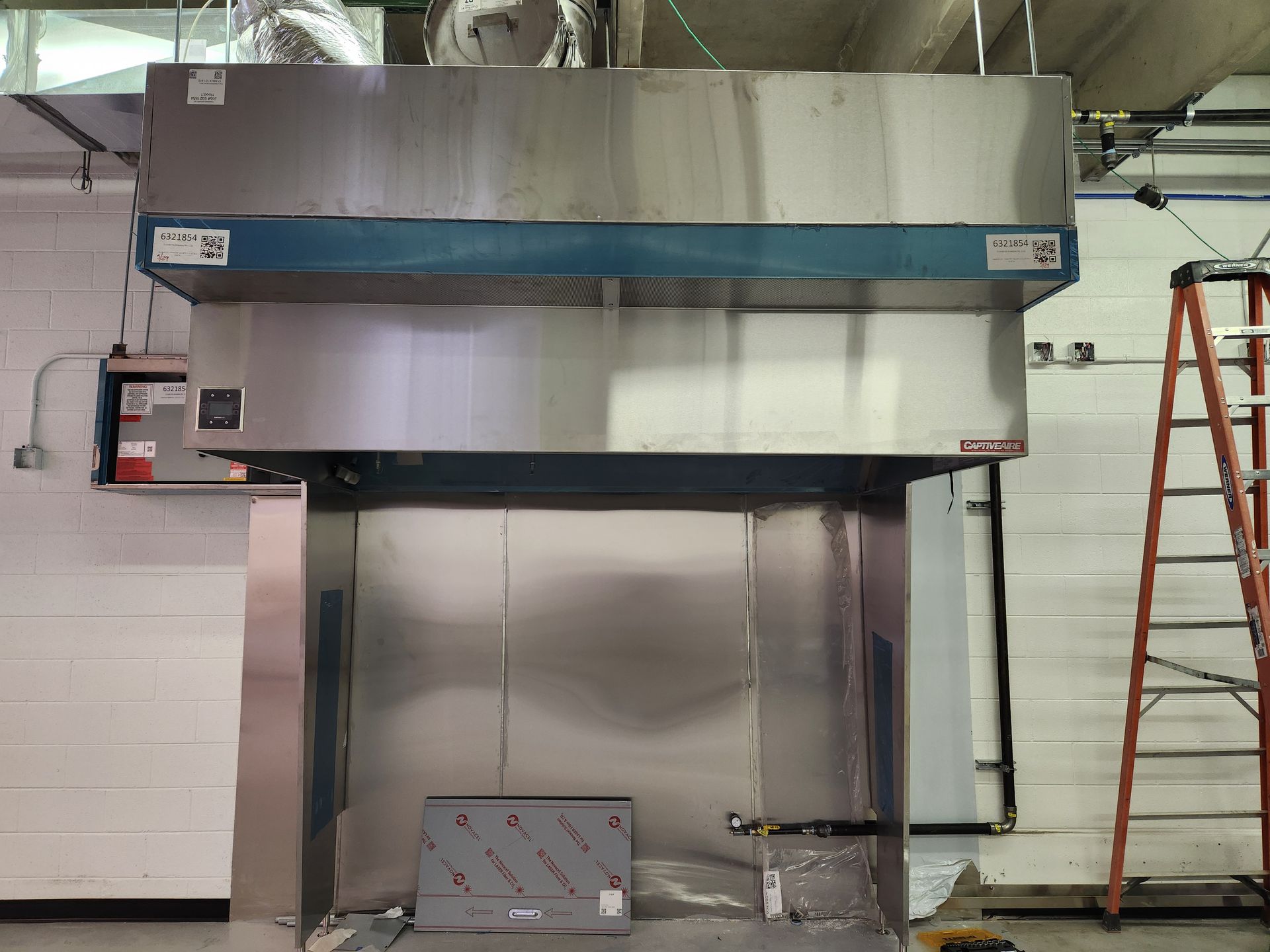 Stainless steel laboratory fume hood, mounted with ductwork, near a ladder.