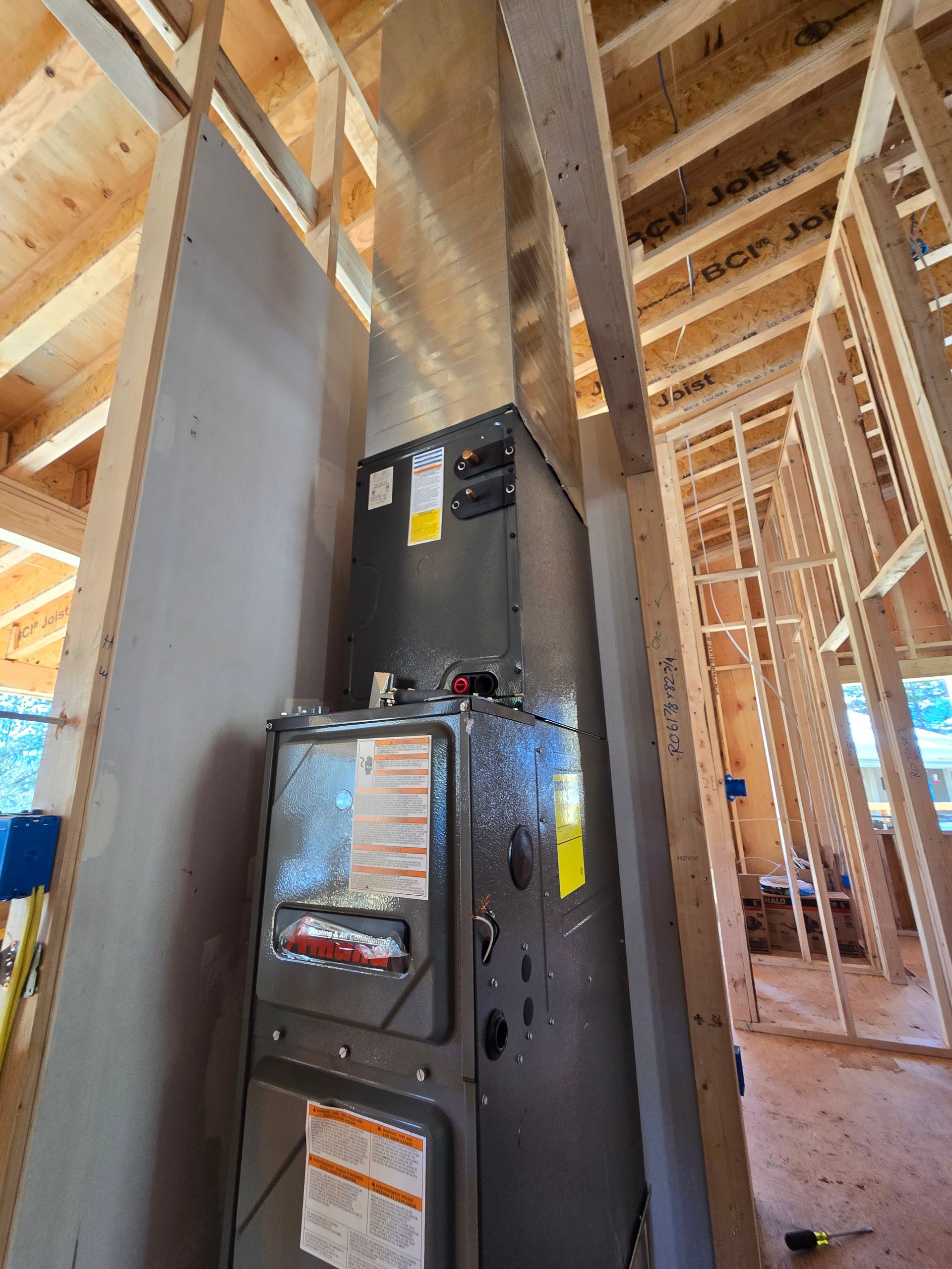 A tall, gray Rheem water heater in a room with blue walls, copper pipes, and a digital display.