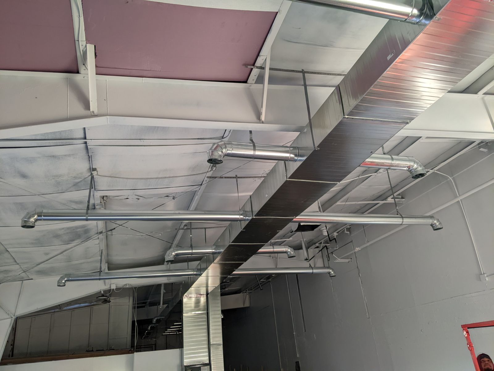 HVAC ductwork and pipes installed on a white ceiling with insulation.