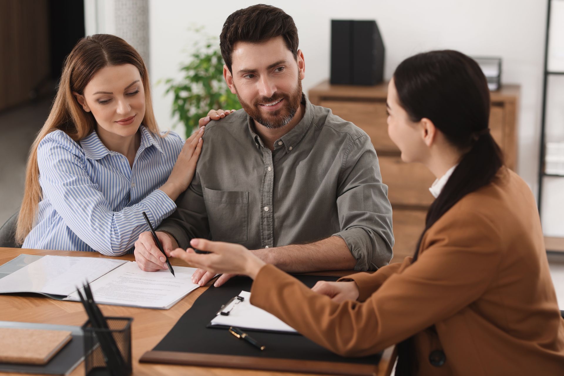 Couple consults with a professional; woman points at documents as man and woman listen.