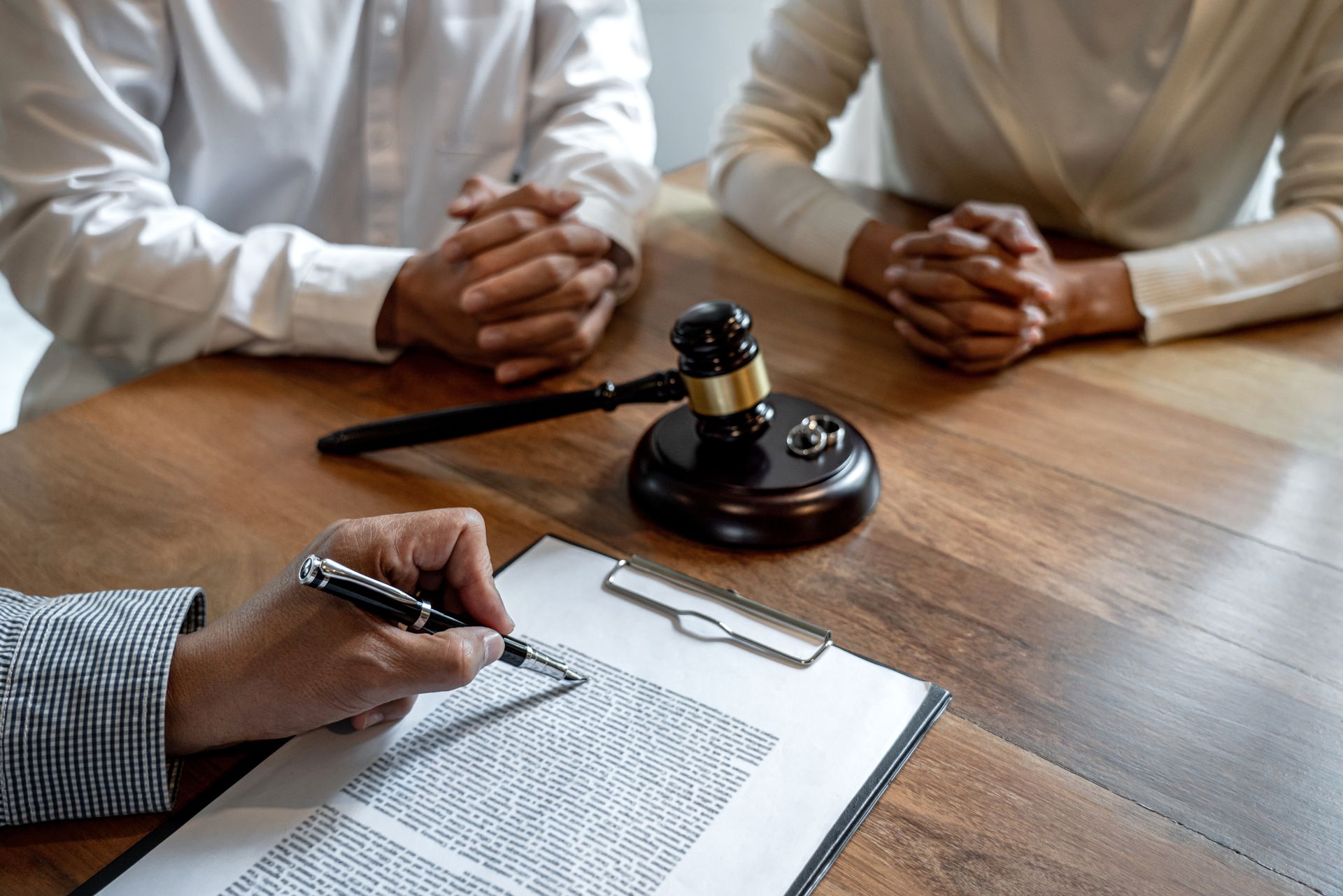 Couple at table with lawyer, gavel, and document.