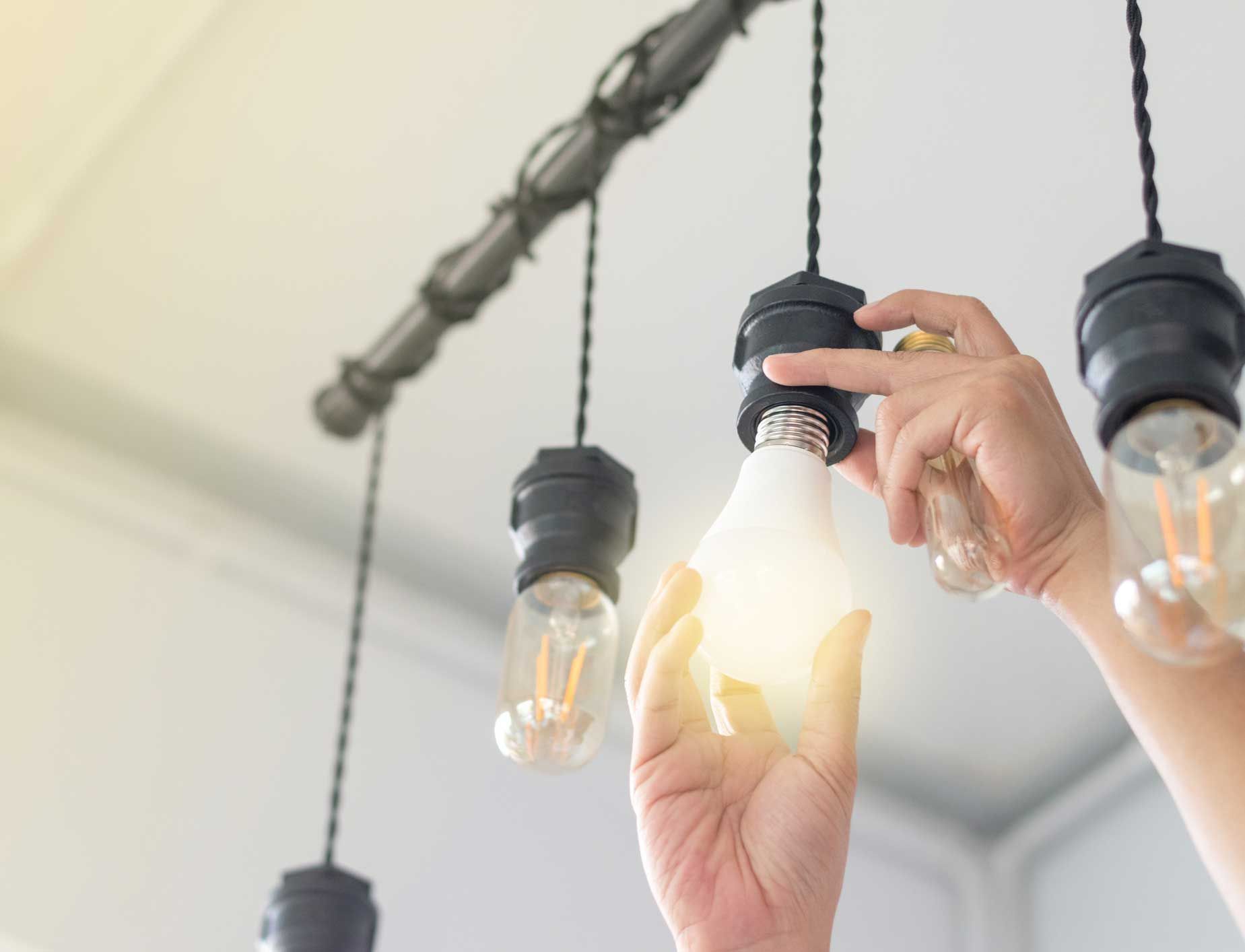 A person is changing a light bulb in a chandelier.