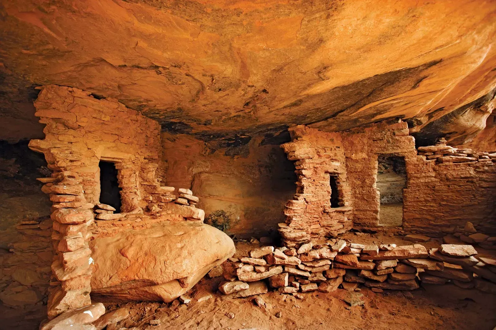 Ancient cliff dwellings built into red rock, showcasing the architectural ingenuity of past civilizations.