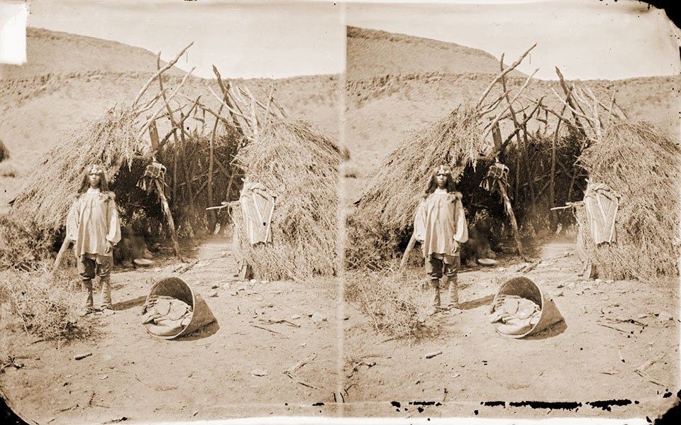 Southern Paiute Boy standing outside a wikiup in Southern Utah