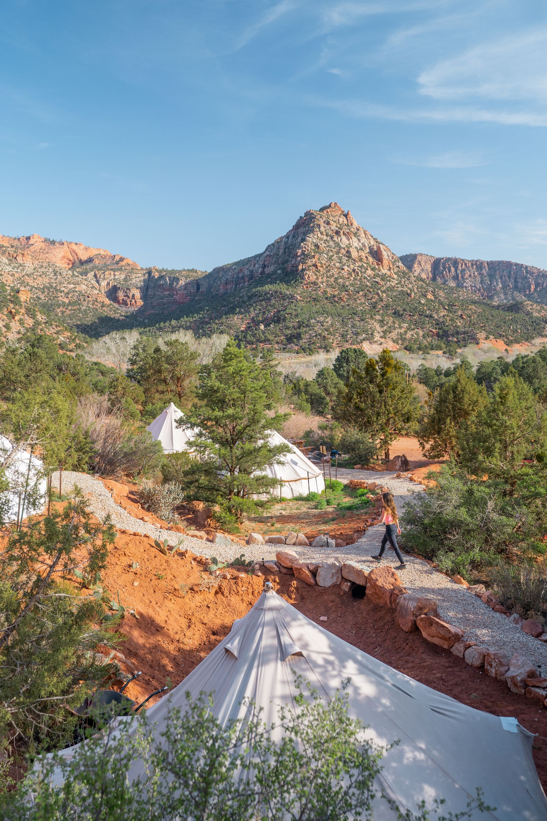 A guest walking along a pathway through Zion Glamping Adventures, with luxury tents and scenic views in the background.