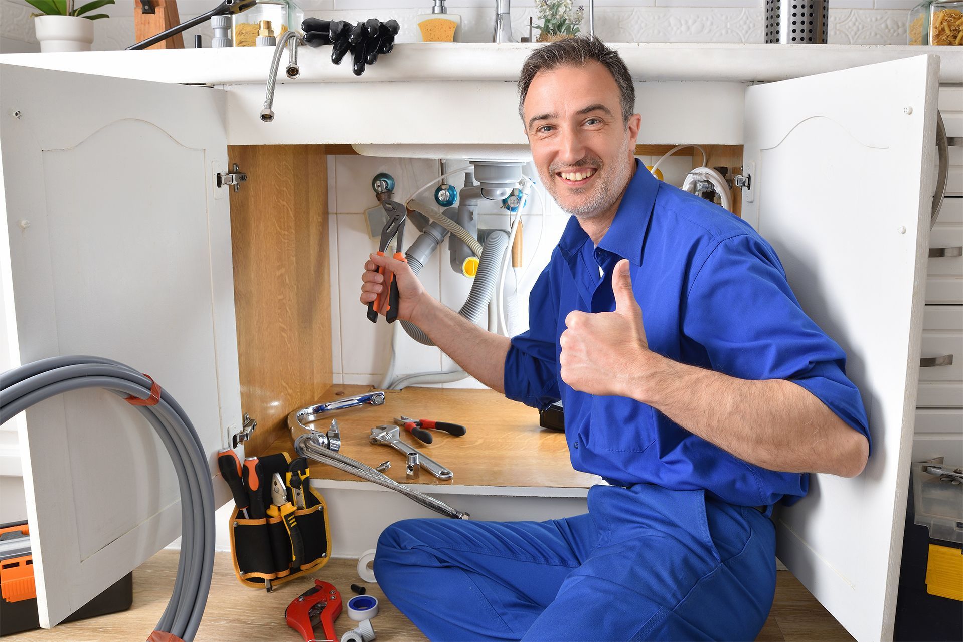 Smiling Plumber Fixing the Kitchen Sink