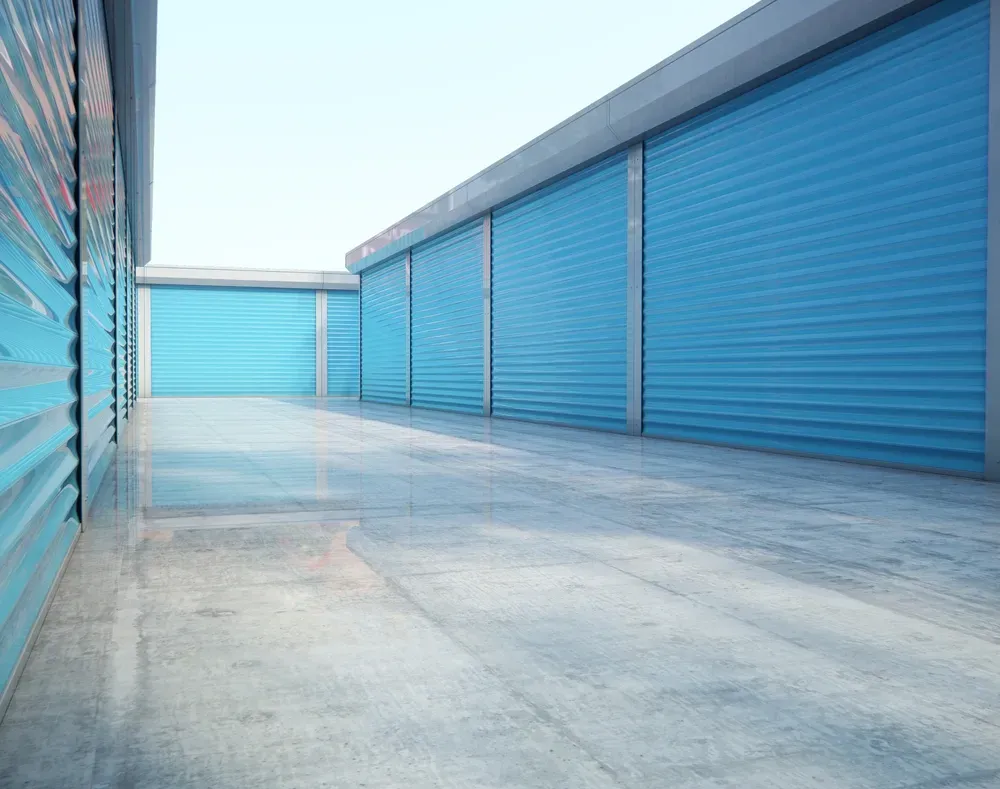 Blue storage unit doors along a concrete corridor, bright sky above. — Gympie Southside Mini Storage in Southside, QLD