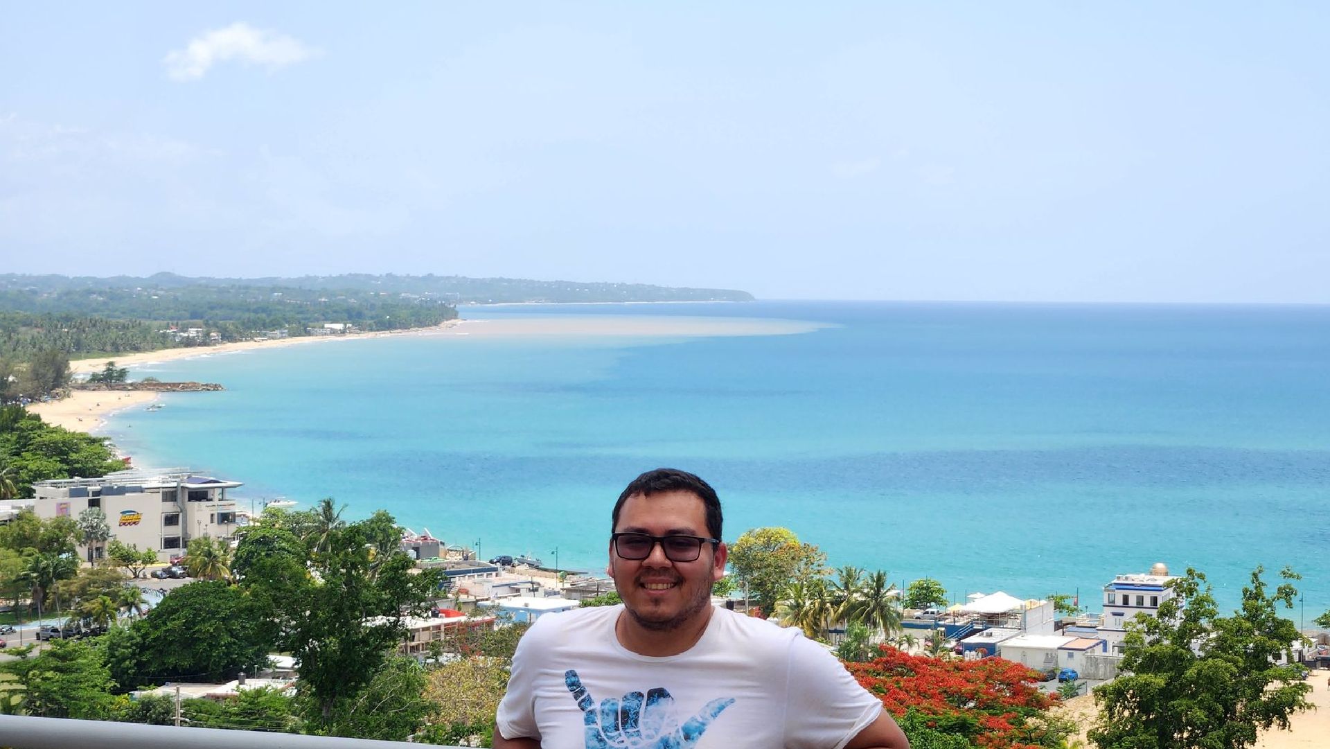 A man is standing on a balcony overlooking the ocean.