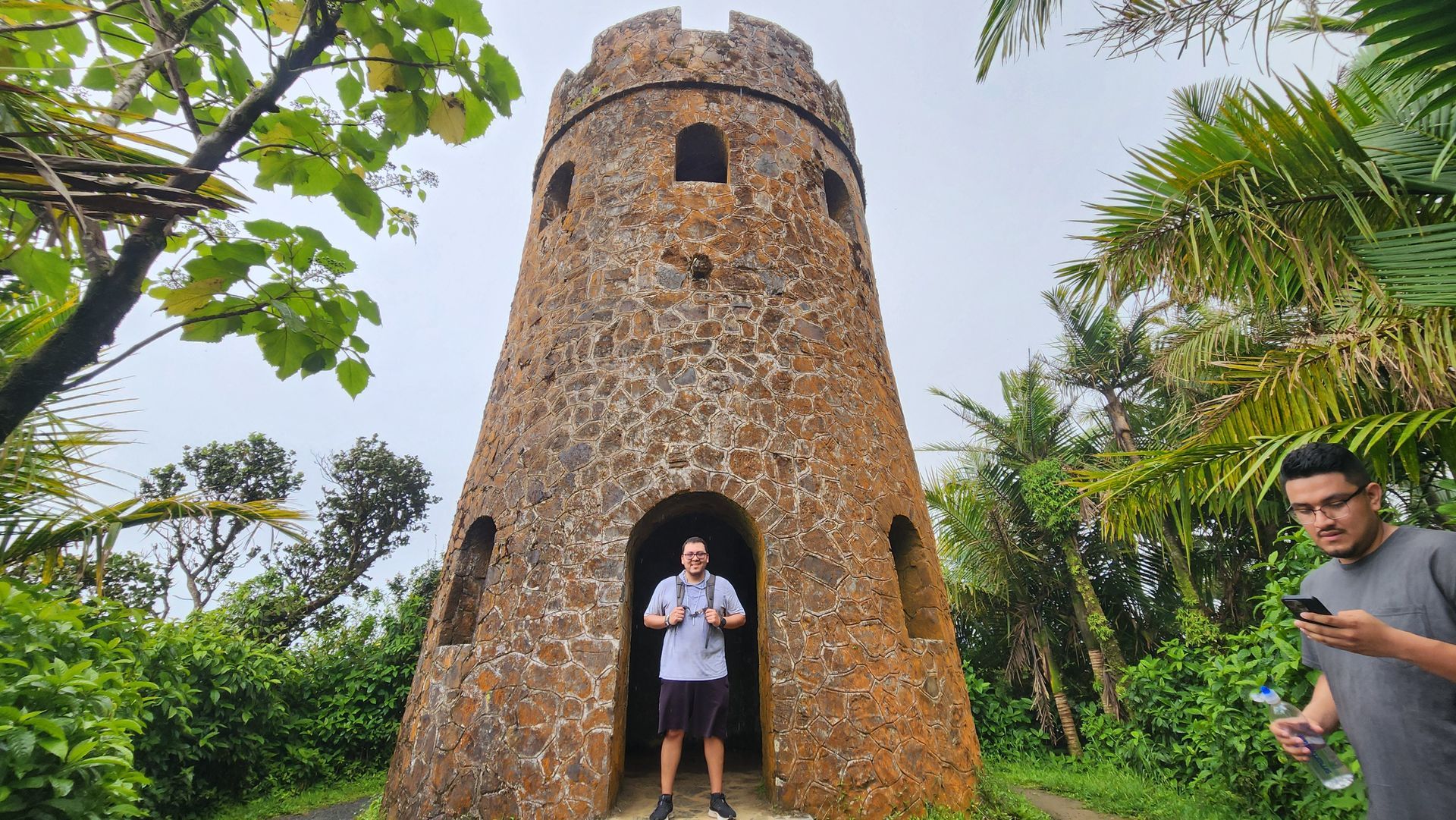 Two men are standing in front of a stone tower.
