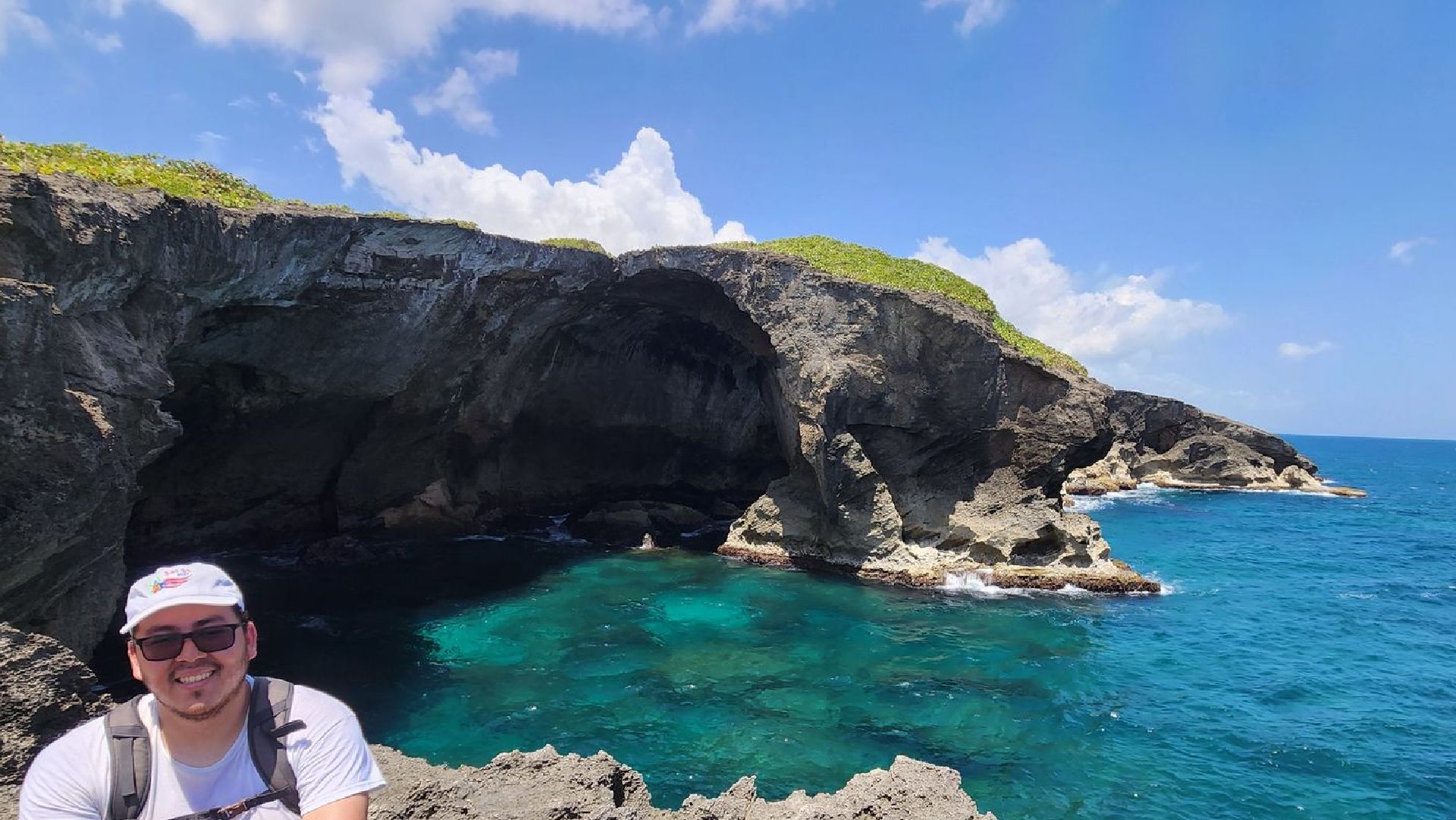 A man is standing on a rocky cliff overlooking the ocean.
