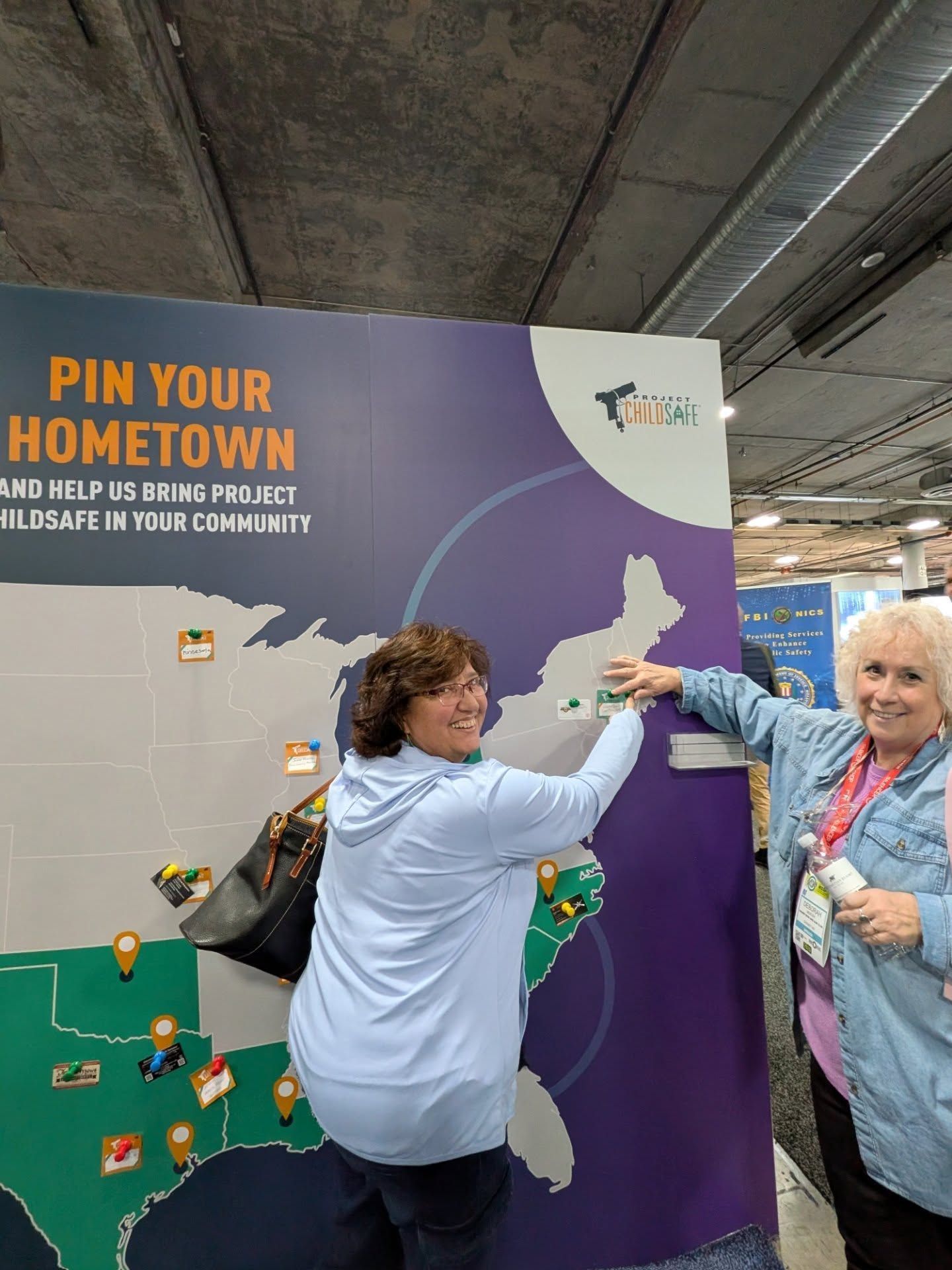Two people pin their hometowns on a US map display at a Project ChildSafe booth.
